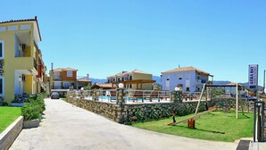 Um edifício residencial com vários andares, varandas, piscina e um muro de pedra.