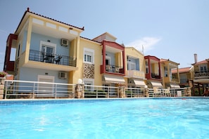 A multi-story hotel with balconies, a swimming pool, and a clear sky. - Gera Bay Studios and Apartments (Lesvos)
