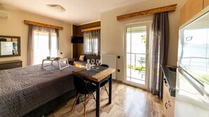 Quarto de hotel com cama, mesa de jantar com cadeiras, televisão e vista para o exterior.