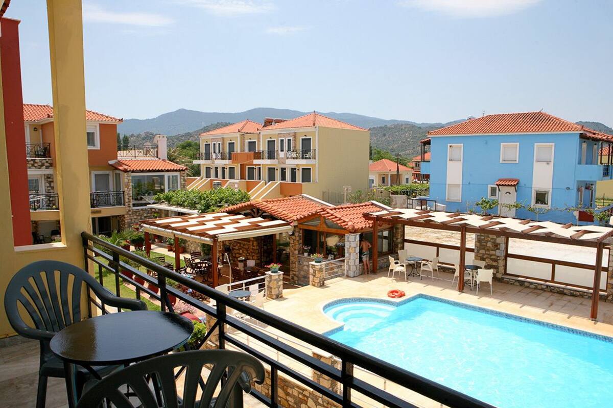 A hotel with a swimming pool, outdoor seating, and a view of the mountains.