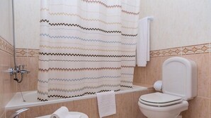 A bathroom with a shower curtain, a toilet, a sink, and a towel rack. - Vila Marachique (Portimão)