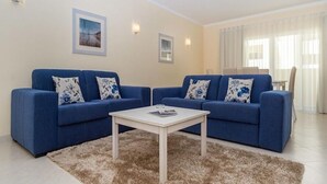 A living room with two blue sofas, a white coffee table, and a fluffy rug. - Vila Marachique (Portimão)