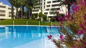 A swimming pool with a clear blue water surface, surrounded by a well-maintained lawn and palm trees. - Vila Marachique (Portimão)