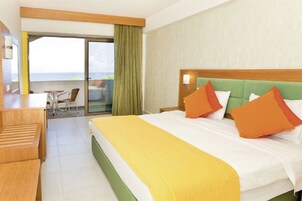 Habitación de hotel con cama, escritorio, silla y vista al océano.