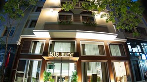 Un hotel con un llamativo letrero 'BIRBY', amplias ventanas y plantas en macetas al frente.
