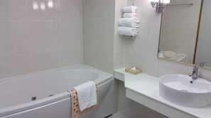 A modern bathroom with a bathtub, a sink, and a mirror. - The Ariston (Bangkok)