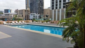 A rooftop pool with lounge chairs and a view of surrounding buildings. - The Ariston (Bangkok)