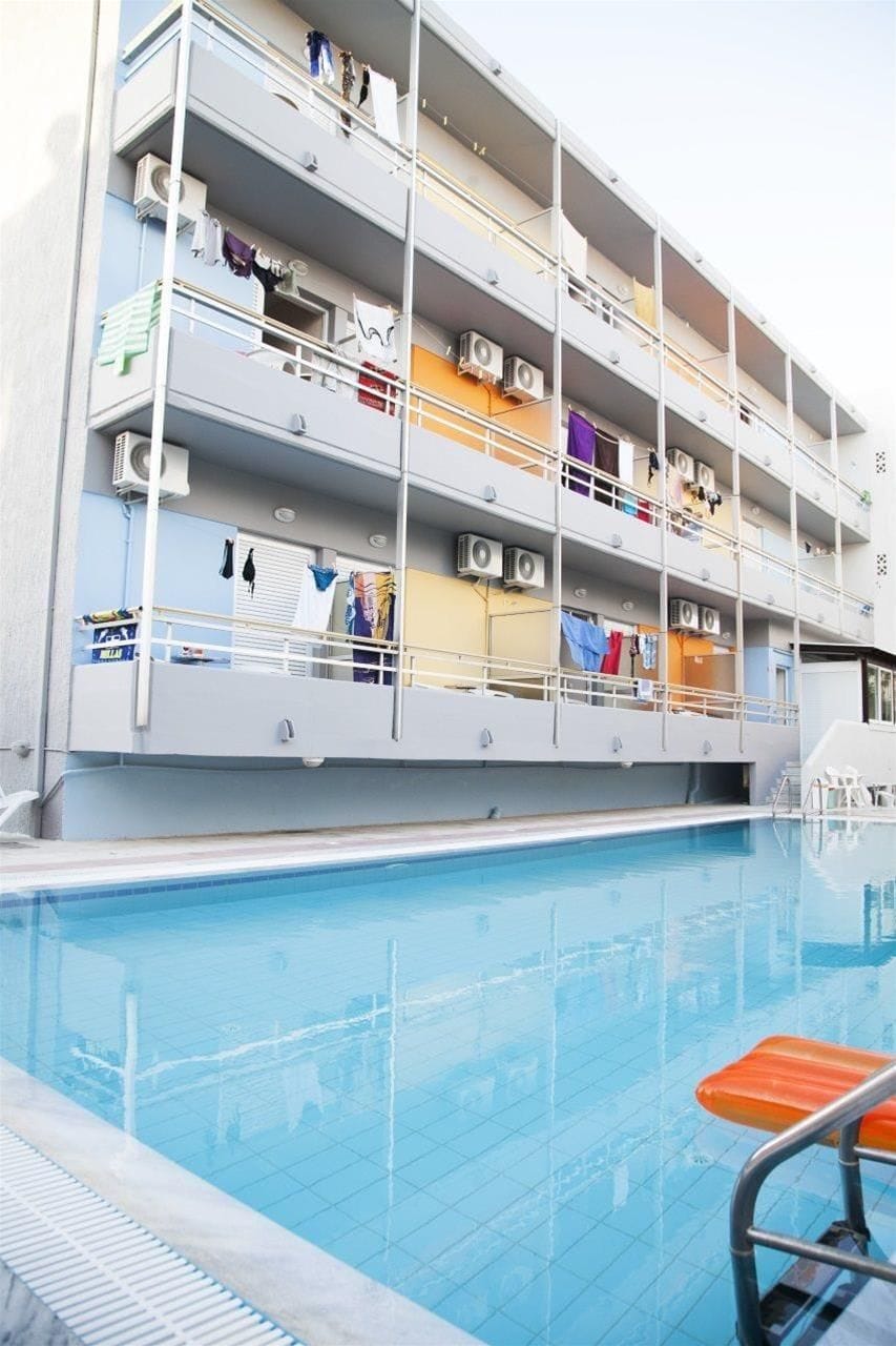 Een meerhoog gebouw met balkons, airconditioners en een zwembad.