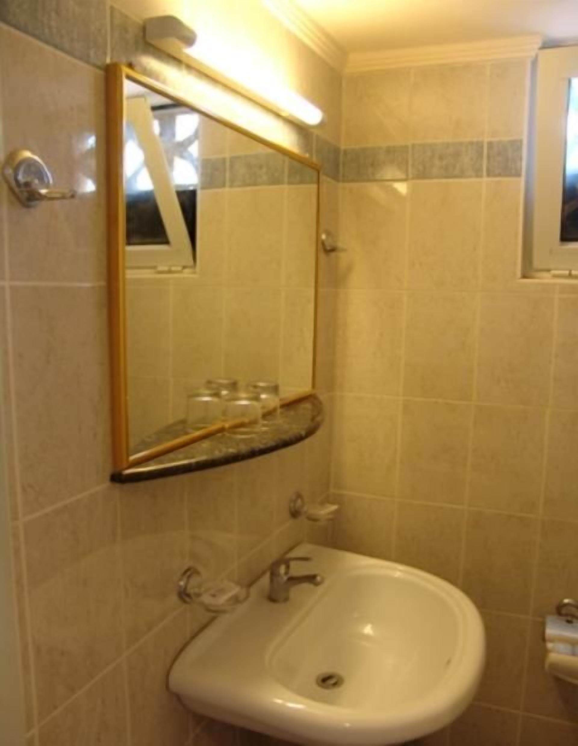 A bathroom with a sink, mirror, and tiled walls.