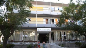 A hotel entrance with a sign reading "Theonia Hotel". There are steps leading up to the entrance, and outdoor seating with tables and chairs. - Theonia (Kos)