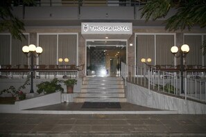 L’entrée de l’hôtel Theonia se distingue par un escalier en marbre, des plantes en pot et une rampe en métal.