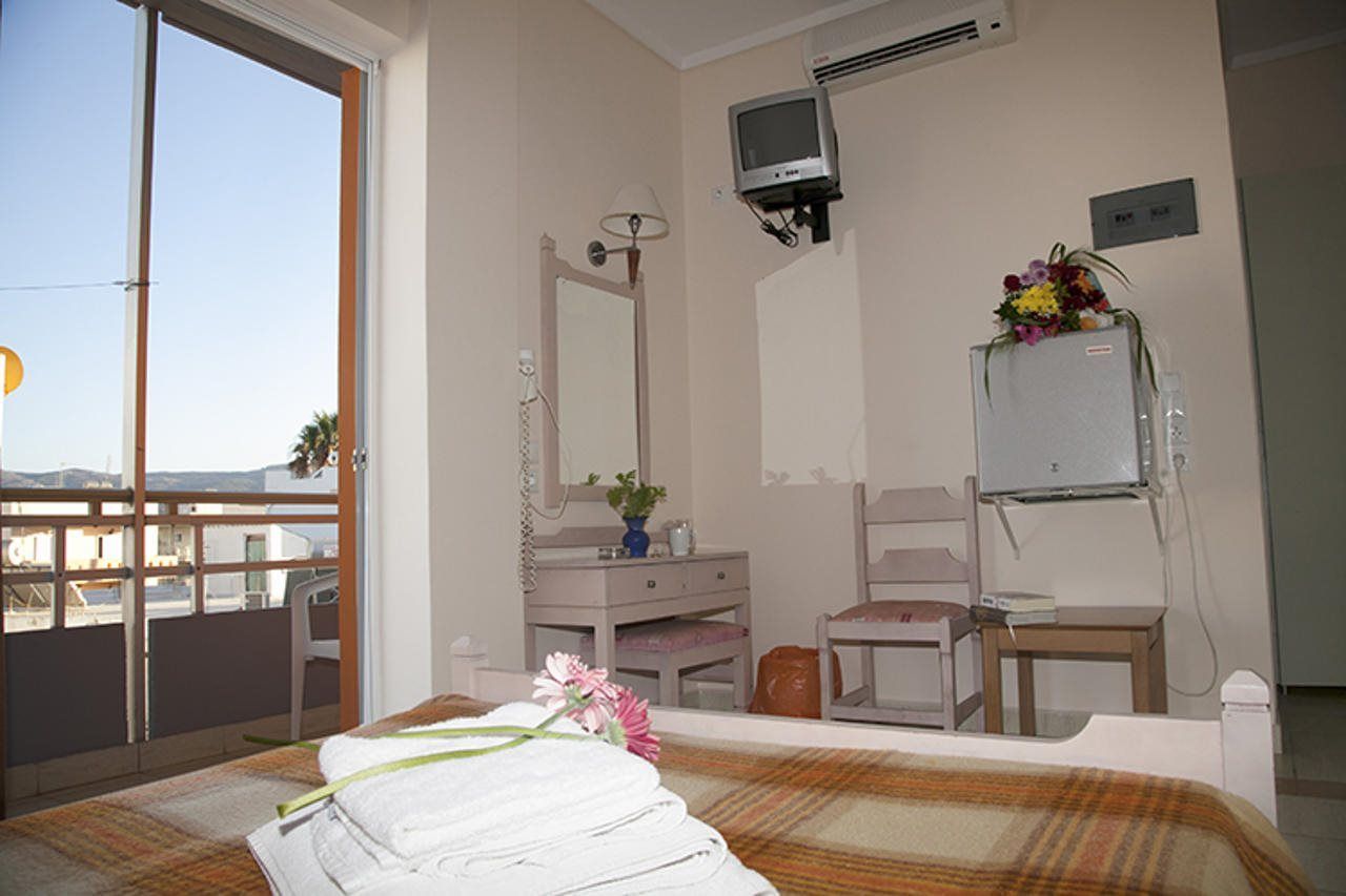 A hotel room with a bed, a desk, a chair, a vanity with a mirror, and a television.