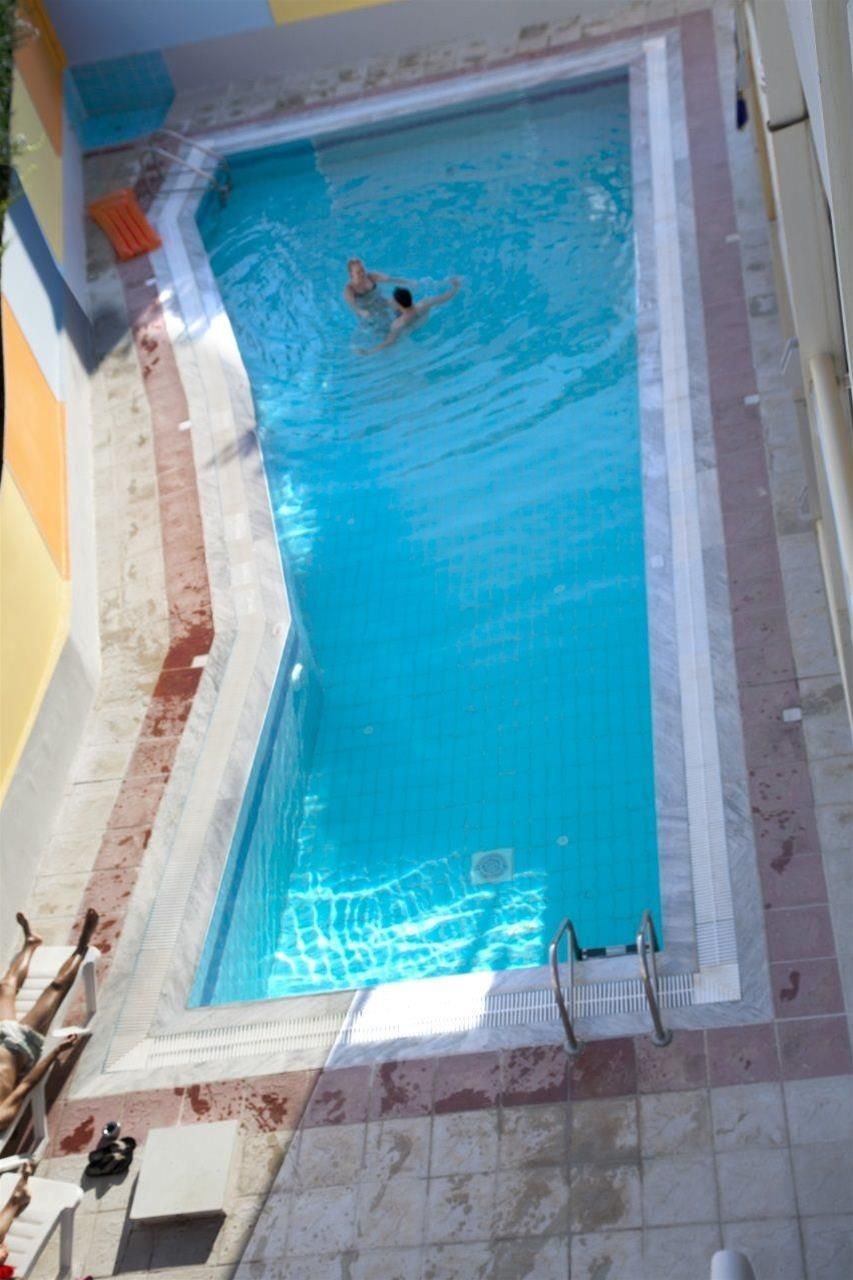 A rectangular swimming pool with a tiled edge, a ladder on one side, and a person swimming.