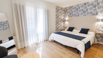 Un dormitorio con cama, una silla, una mesa redonda y un espejo.