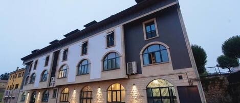 A multi-story building with a modern architectural style, featuring arched windows and a stone facade.