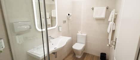 Un baño moderno con cabina de ducha de vidrio, un lavamanos blanco, un inodoro y un perchero para toallas.