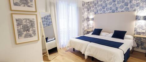 Quarto com cama, espelho, mesa de cabeceira e janela com cortinas.