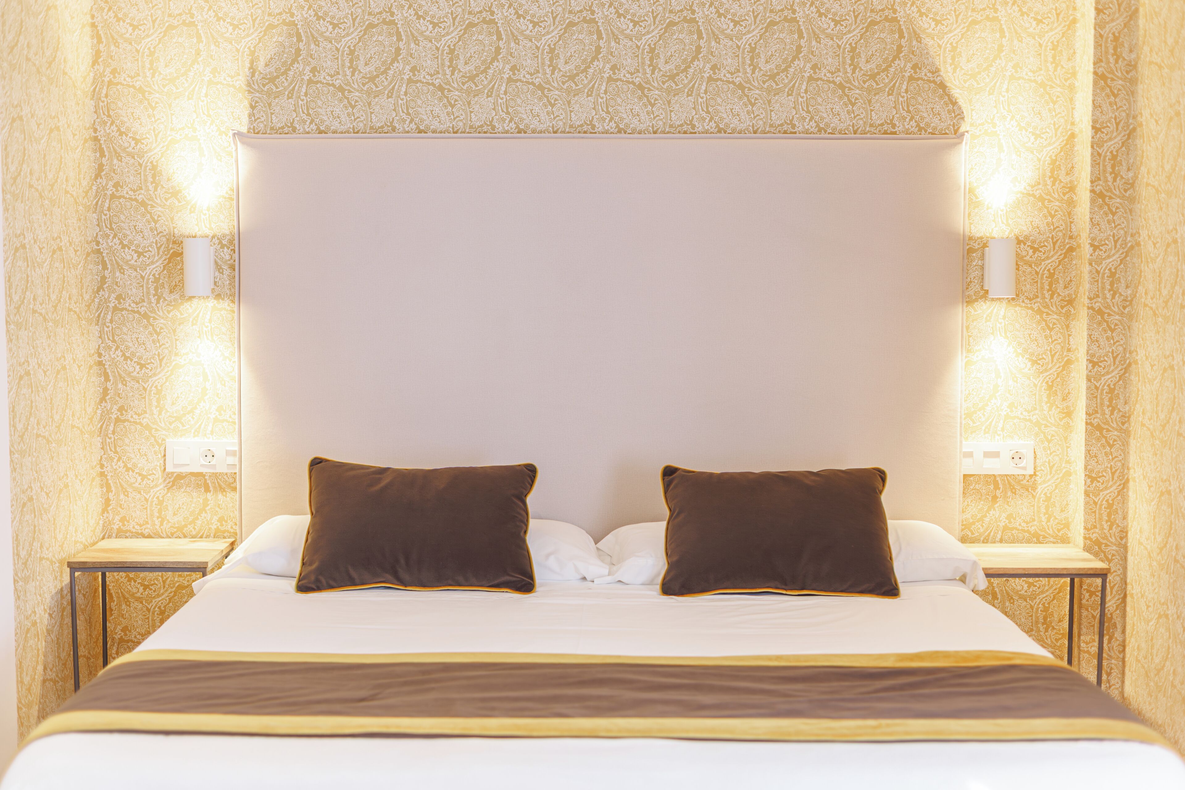 Habitació d'hotel amb un llit gran, dues taules de nit i aplics de paret.