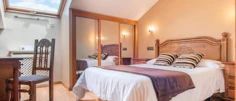 Un dormitorio con una cama grande, una silla de madera, un escritorio y un tragaluz.