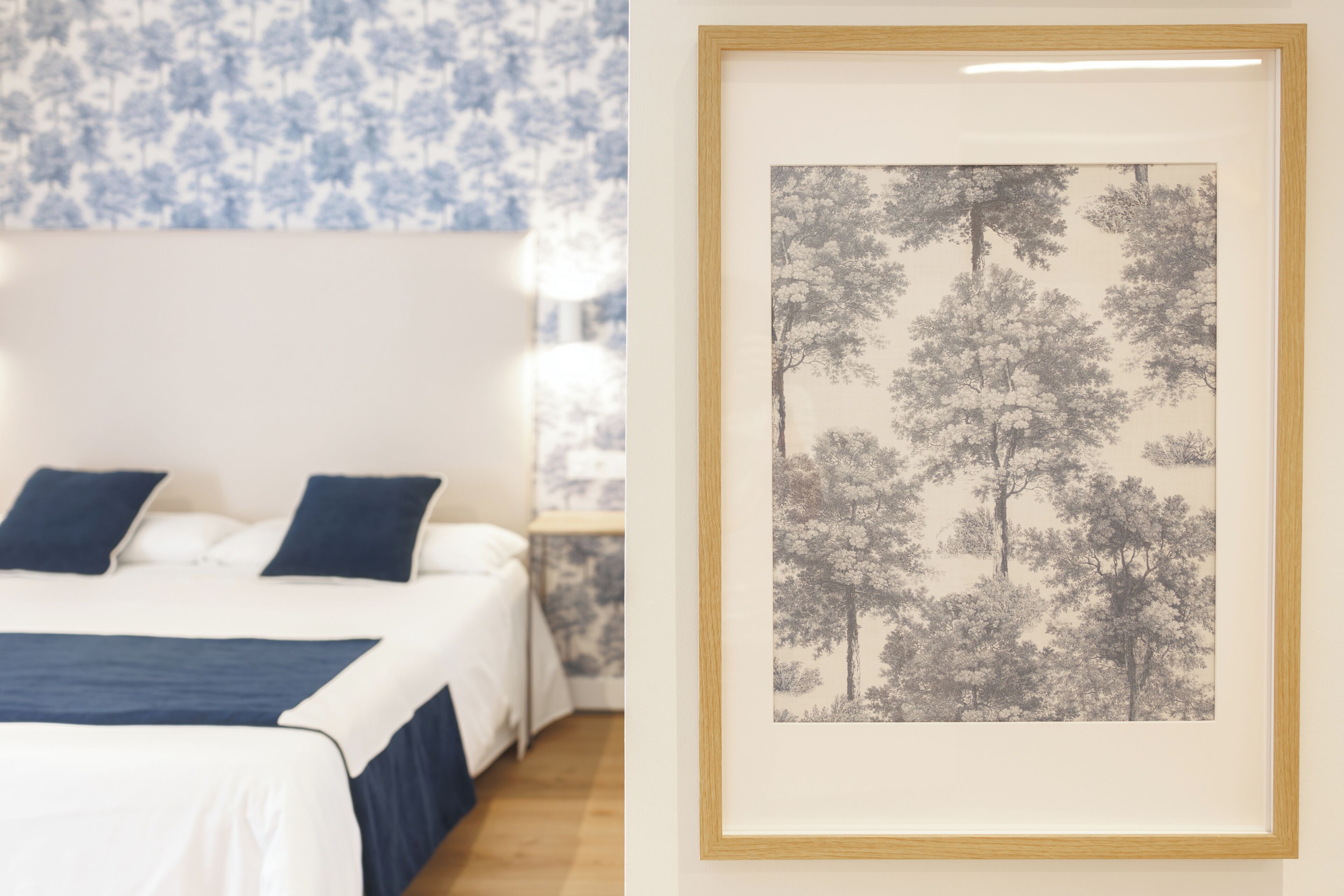 A bedroom with a bed, pillows, a nightstand, and a framed picture on the wall.