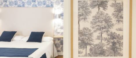 A bedroom with a bed, pillows, a nightstand, and a framed picture on the wall.
