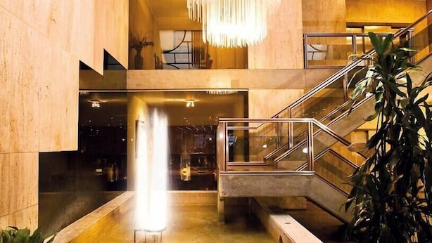 Een modern interieur met een centraal waterpartij, een trap en een kroonluchter.