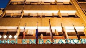 Een hotelschild met de naam 'Hotel Embajador' en een rij vlaggen ervoor.