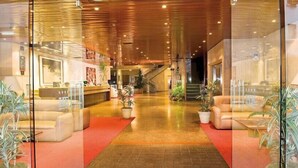 Een ruime lobby met een houten plafond, een receptiebalie en diverse zithoeken.