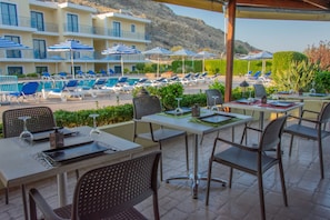 A rooftop terrace with outdoor seating, umbrellas, and a pool area in the background. - Rafael Hotel - Adults Only (Rhodes)