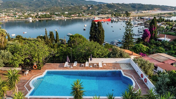 Una piscina con vistas a un lago, barcos y vegetación circundante.