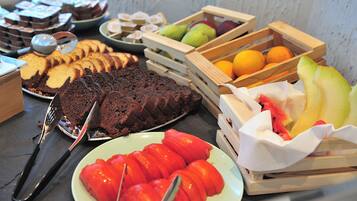Una mesa de buffet con diferentes opciones de comida, como pan en rebanadas, pasteles, frutas y verduras.
