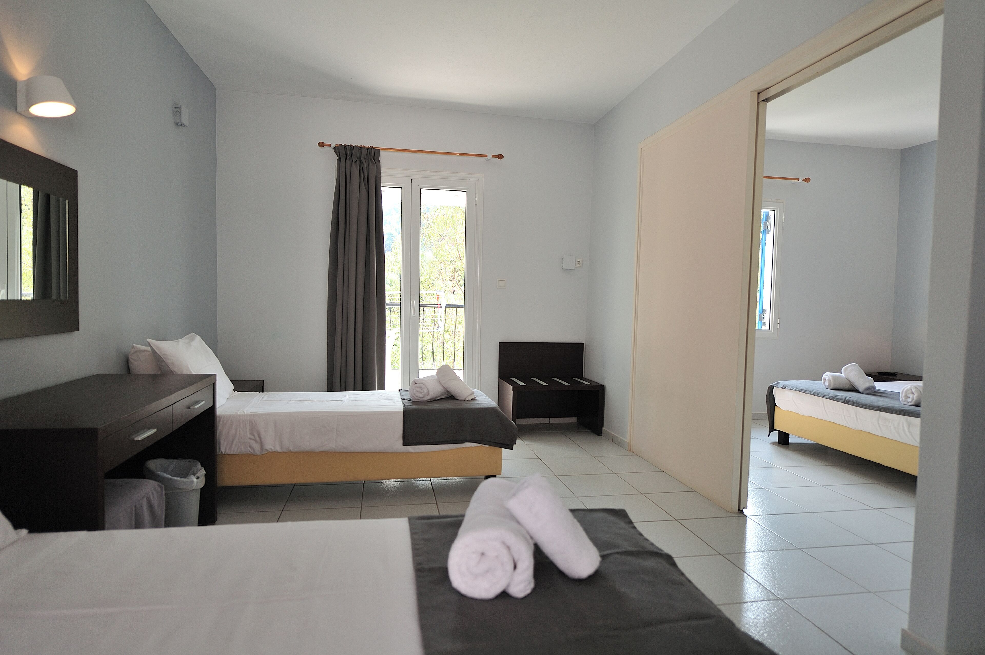 A modern hotel room with a bed, a desk, a chair, and a small seating area.