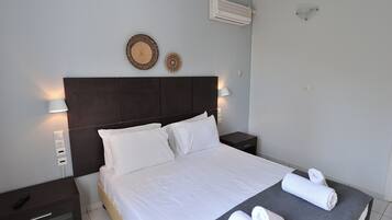 A neatly made bed with white linens, a dark headboard, and two wall-mounted lamps.