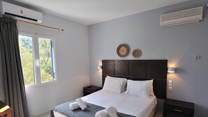 Una cama bien hecha con toallas, una mesita de noche y un aire acondicionado instalado en la pared.