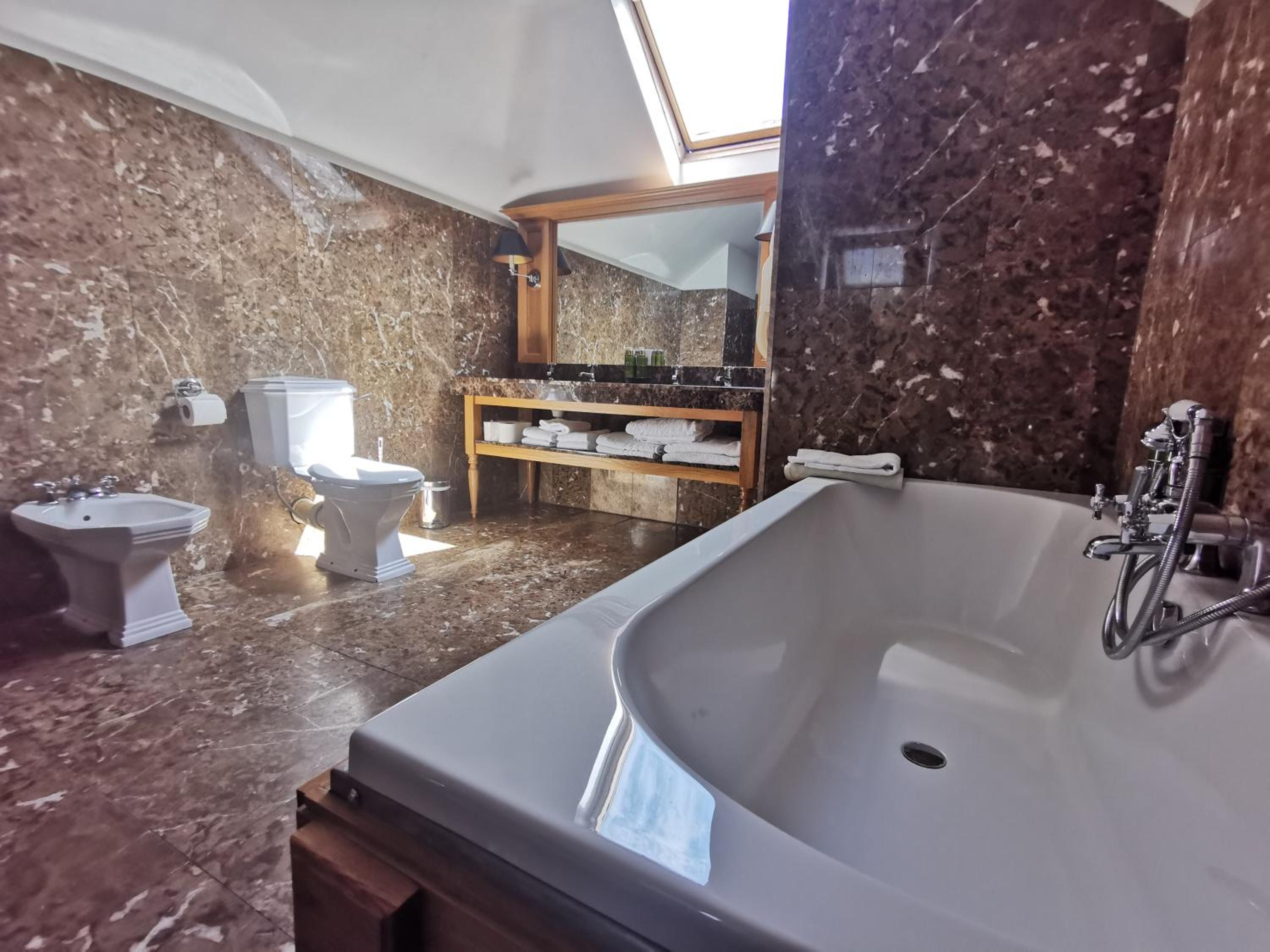 Un baño con una bañera grande, dos lavamanos, un inodoro y un tocador con espejo.