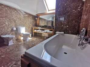 A bathroom with a large bathtub, two sinks, a toilet, and a vanity with a mirror. - Langton House Hotel (Kilkenny)