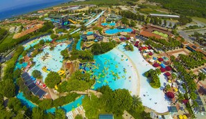 Een groot waterpark met meerdere zwembaden, glijbanen en een strandgedeelte.