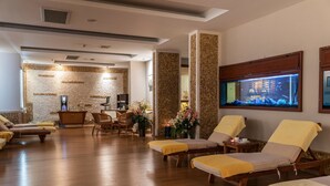 A spa area with wooden flooring, sun loungers, a reception desk, and a large aquarium. - Aqua Fantasy Aquapark Hotel & Spa - All Inclusive (Selçuk)