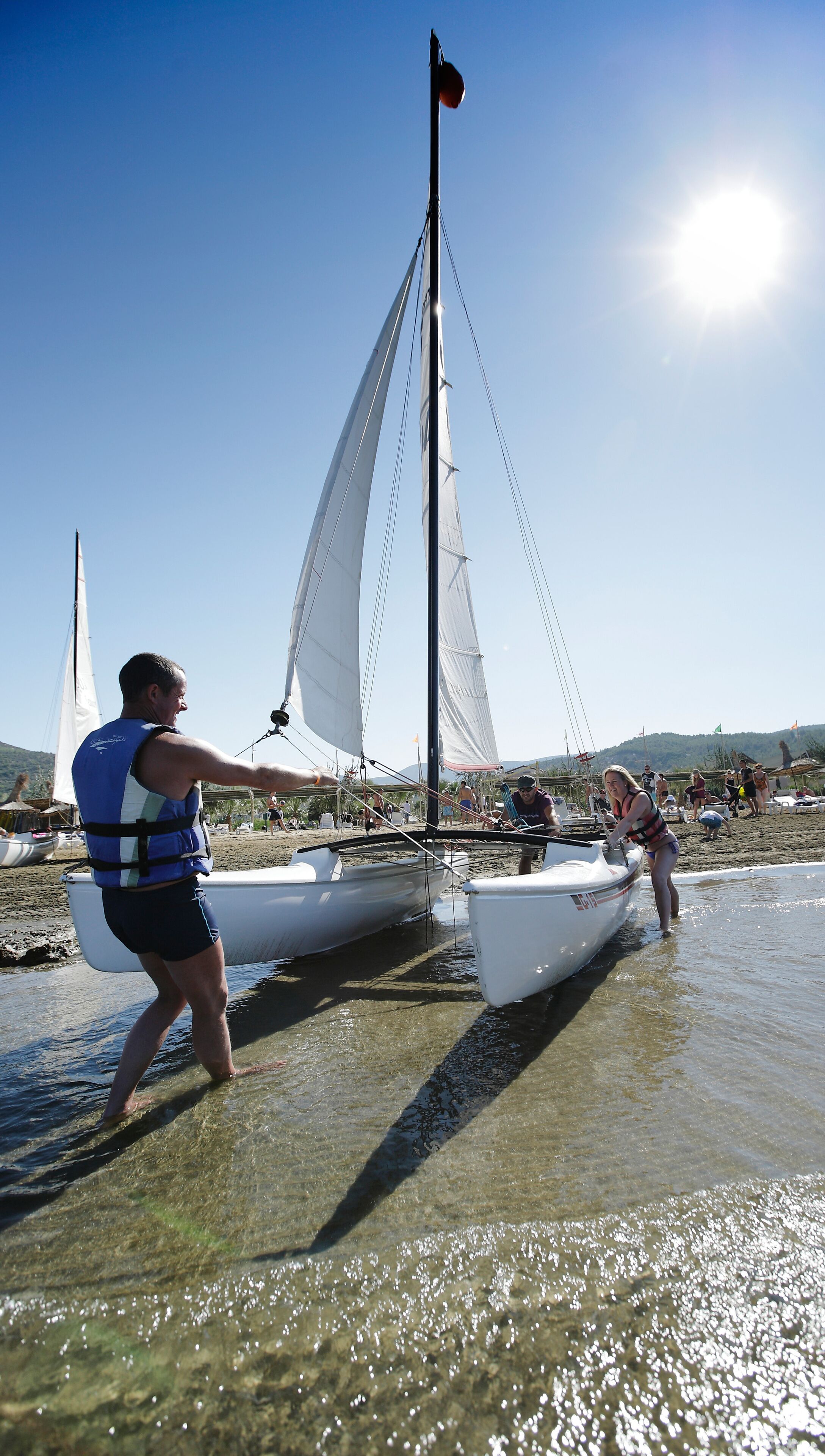 Een zeilboot op het strand, met mensen in de buurt.