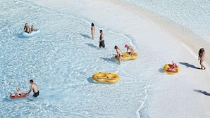 A beach scene with people in water and on the sand, some on inflatable rings. - Aqua Fantasy Aquapark Hotel & Spa - All Inclusive (Selçuk)