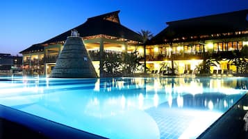 Una piscina techada, una piscina al aire libre, sombrillas