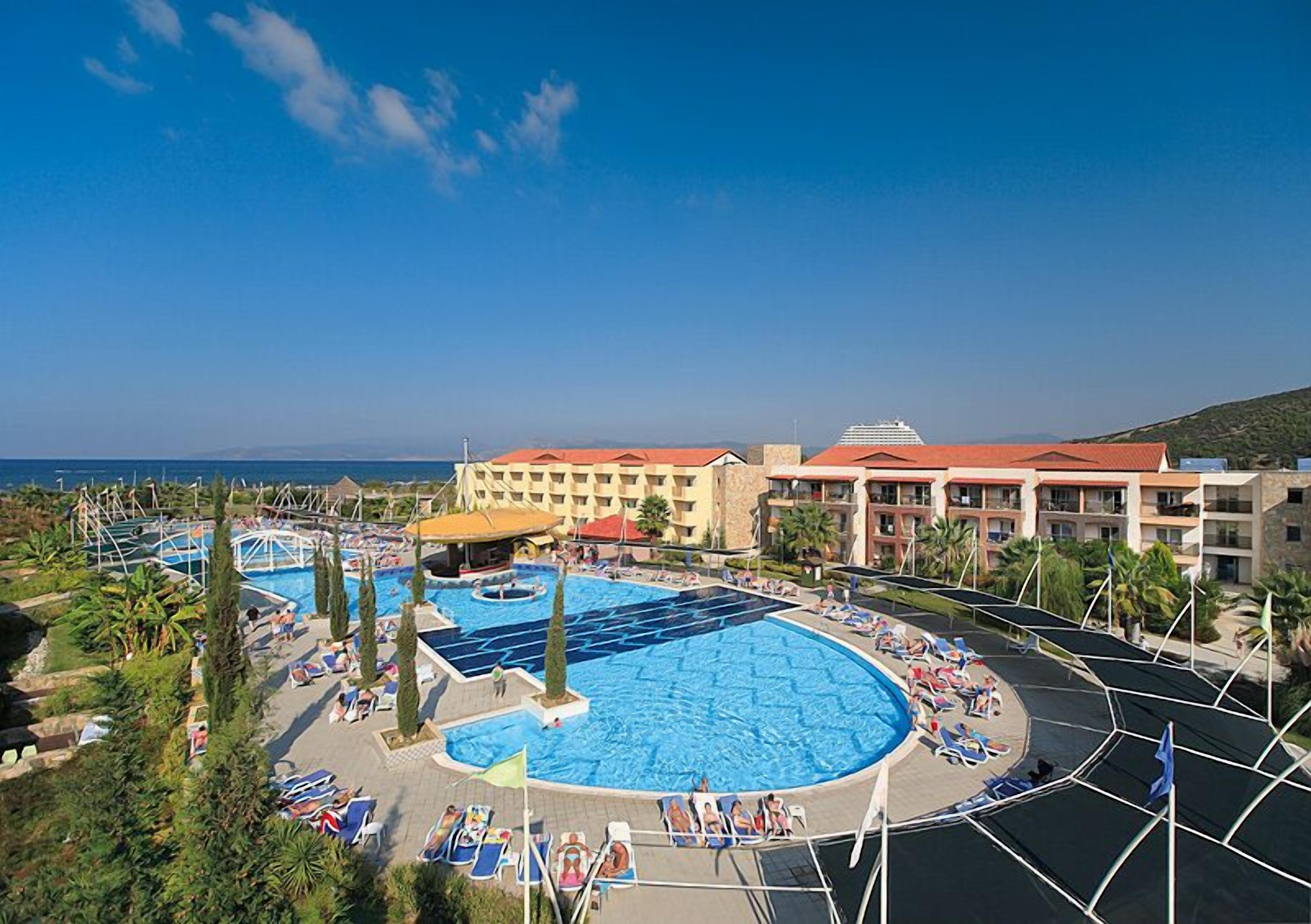 Ein Resort mit mehreren Schwimmbecken, Liegestühlen und Blick auf das Meer.
