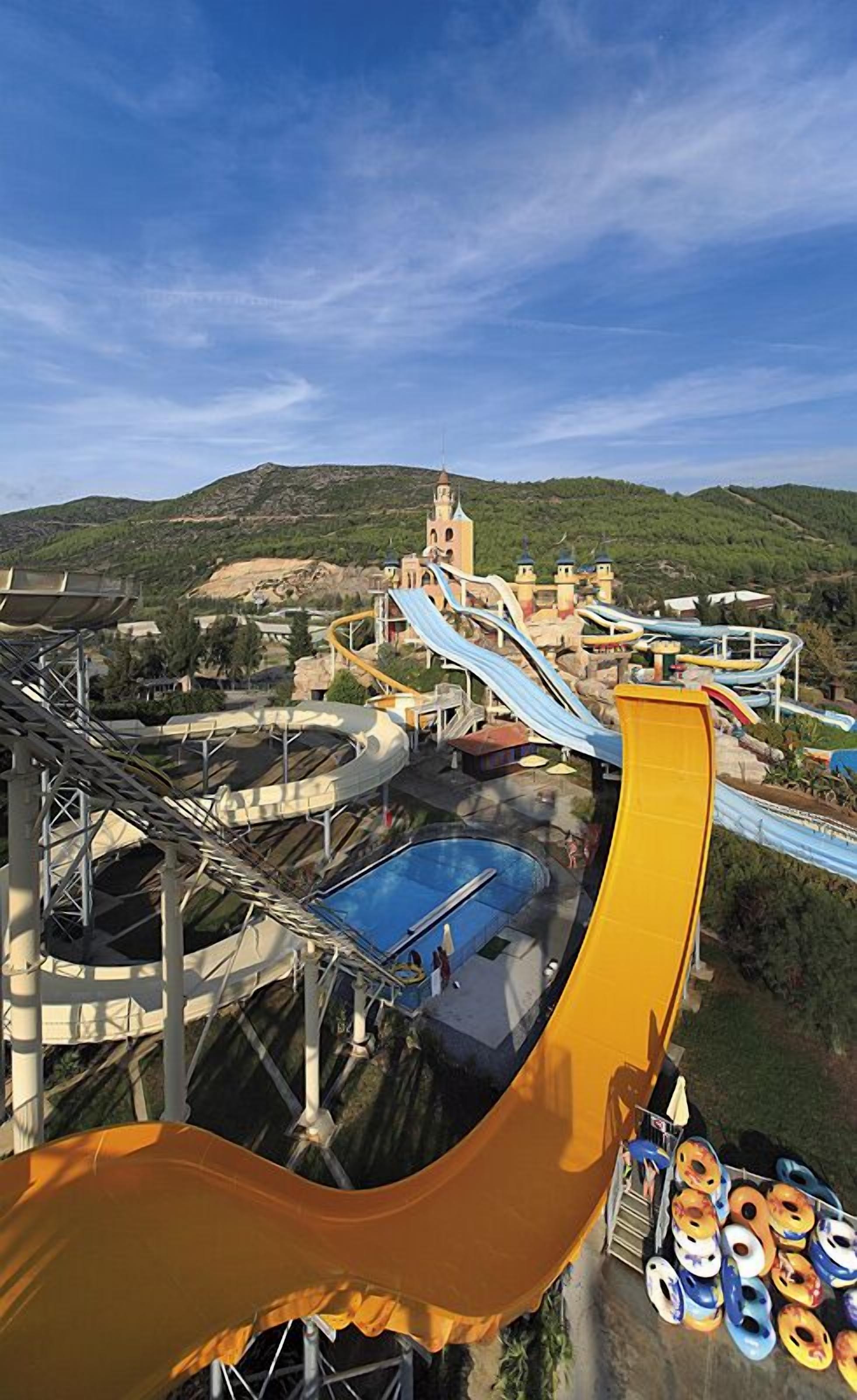A water park with a large yellow water slide, a pool, and a tower structure.
