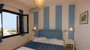 Een slaapkamer met een groot bed, twee nachtkastjes, een raam met gordijnen en uitzicht naar buiten.