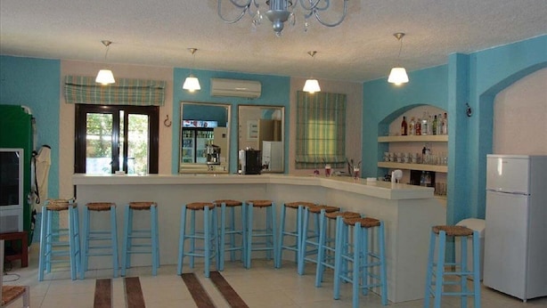 Een keuken met blauwe barstoelen, een witte koelkast en een kroonluchter.