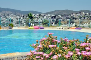 A swimming pool with colorful lounge chairs and a flower bed in the foreground. - Aparthotel Siesta Beach Bodrum (Bodrum)
