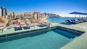 A swimming pool with lounge chairs and umbrellas, overlooking a coastal cityscape. - Selomar (Benidorm)