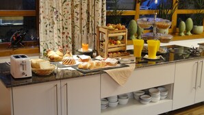 Un buffet de petit-déjeuner proposant une variété de pains, de viennoiseries, de fruits et de boissons, le tout présenté sur un comptoir.