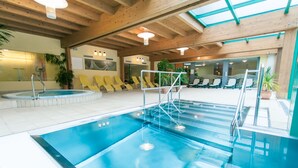 Une piscine intérieure avec un plafond en bois et plusieurs chaises longues.