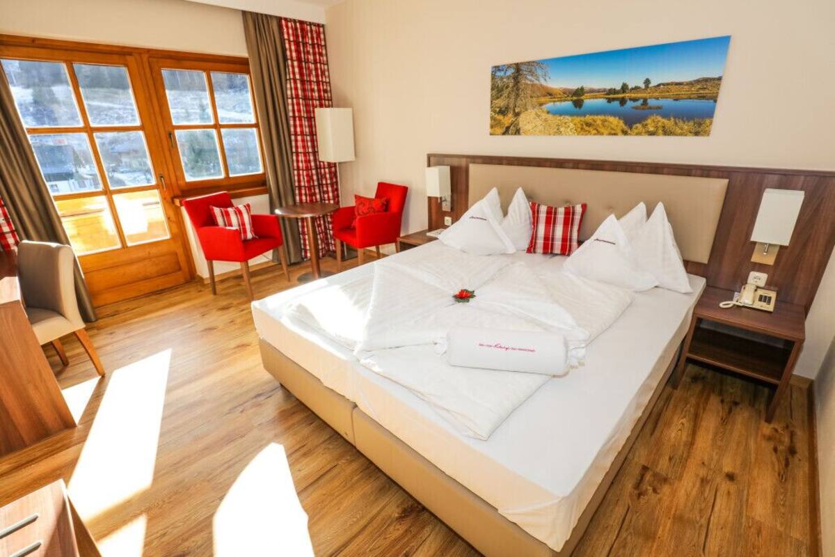 Ein Hotelzimmer mit einem großen Bett, einem Schreibtisch, einem Sessel und einem Gemälde an der Wand.